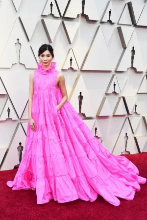 Gemma Chan in a fuchsia ruffled tiered ball gown with high neck at OSCARS 2019 Red Carpet