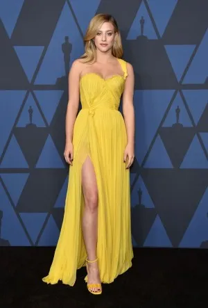 Lili Reinhart attended the 2019 Governors Awards wearing a pleated yellow chiffon one shoulder slit prom dress