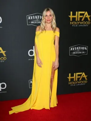 Sienna Miller in a flowing yellow chiffon off the shoulder slit evening prom dress at the 2019 Hollywood Film Awards