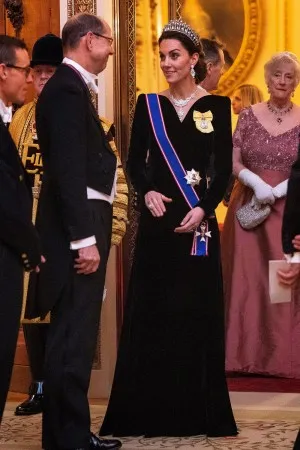 Kate Middleton in a black velvet V neck long sleeve formal gown attending a reception for the Diplomatic Corps 2019