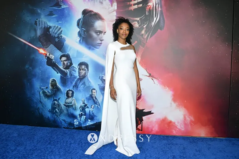 Naomi Ackie white formal gown with a yoke cutout and an asymmetrical cape Naomi Ackie white formal gown with a yoke cutout and an asymmetrical cape
