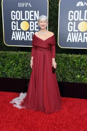 Helen Mirren in a burgundy off the shoulder formal gown with sleeves at the red carpet of 2020 Golden Globes