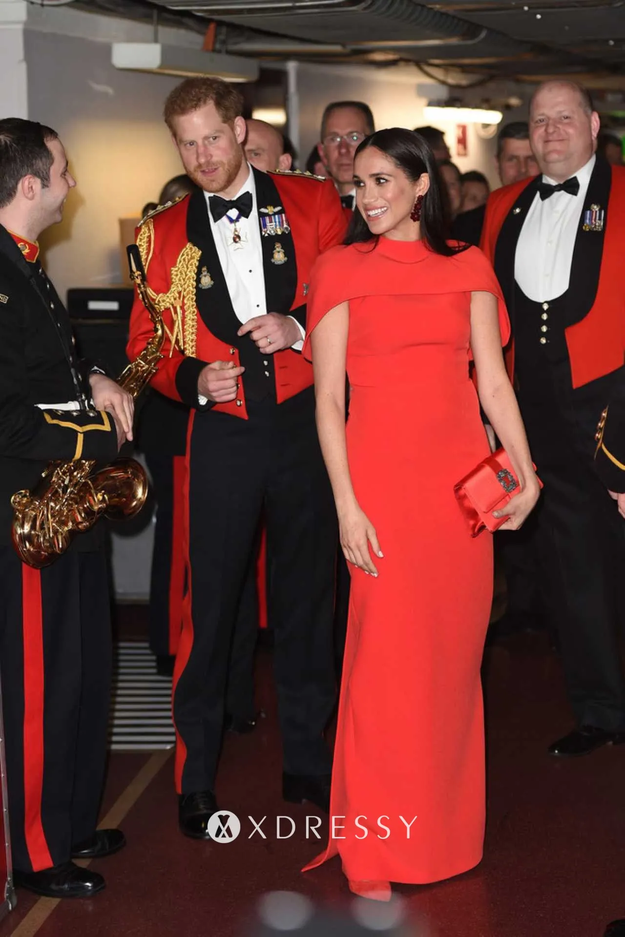 Meghan Markle in a scarlet column formal dress with capelet detailing at the Mountbatten Music Festival 2020